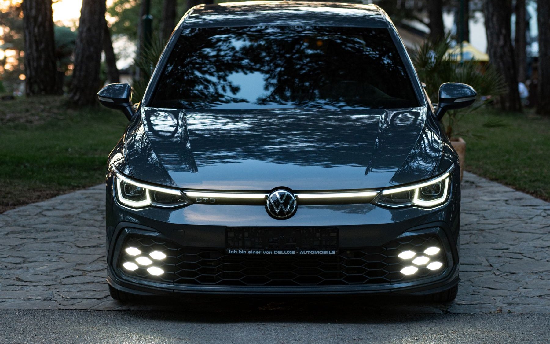 Volkswagen Golf GTI Mk8 with its X-shaped fog lights on at dusk